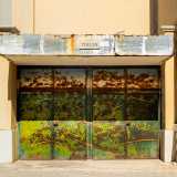 Ed eccoci finalmente davanti a Porta Italia. Fu Milvia Maglione, artista che mescolava Surrealismo e Pop Art, a raffigurare un verde prato illuminato dal sole mediterraneo, che si stagliava su un mare blu sullo sfondo
